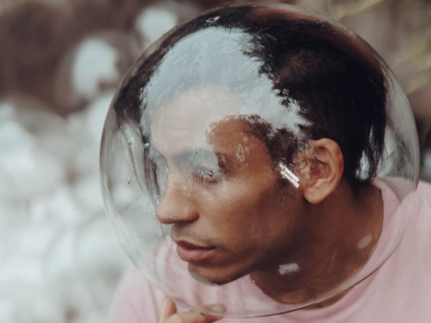a man in pink shirt with his head on a glass ball