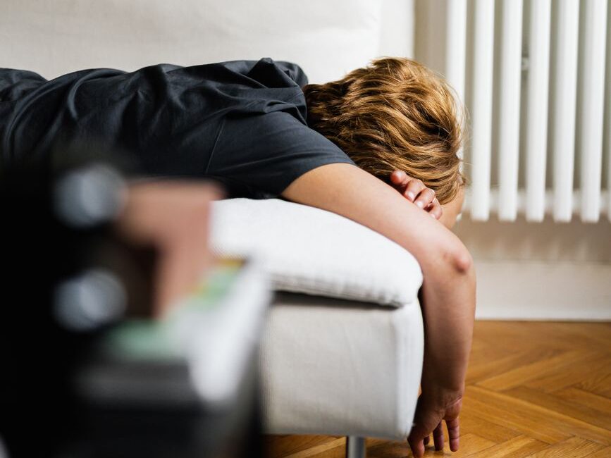 person in black shirt lying on a white sofa